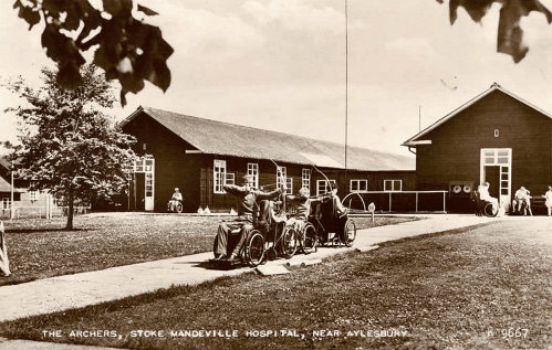 Black and white postcard of the archers outside the huts at Stoke Mandeville.