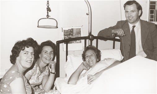 Margaret Maughan as a patient in a bed surrounded by family members